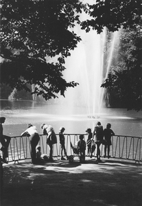 502693 Afbeelding van enkele toeschouwers bij de fontein in de vijver van het Julianapark te Utrecht.